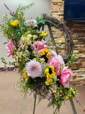 Funeral Floral arrangement on a stand with a stone wall background
