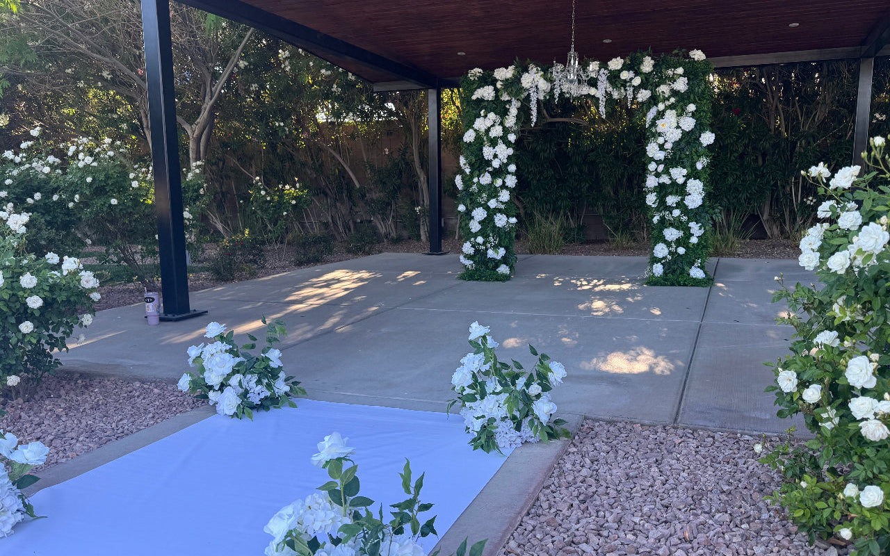 Romantic white floral arch and aisle arrangements for an intimate Las Vegas elopement ceremony with chandelier accents and soft garden-inspired styling.